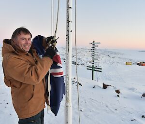 Expeditioner standing beside flagpole with signposts behind him