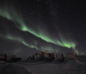 Green Aurora australis above winterised vehicles on the Davis helipad