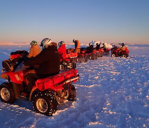 Expeditioners in a line with their quad bikes on the sea ice