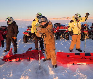 Sea ice drilling practice with expeditioners beside quad bikes