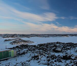 Field hut in foreground with snow landscape in background