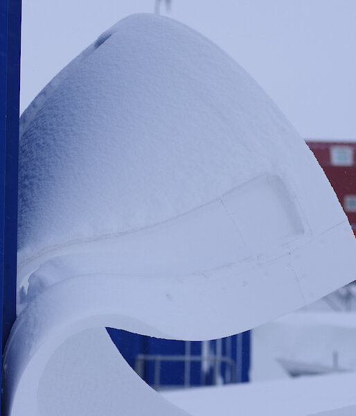 A large wave of snow leeping off an outlying power building on station