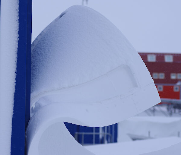 A large wave of snow leeping off an outlying power building on station