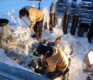 Two expeditioners working beside exposed pipe