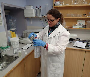 Doctor in white lab coat filling a test tray with a sample of water
