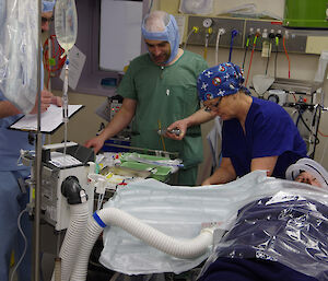 Members of the lay surgical team in surgical gowns in the theatre practising procedures