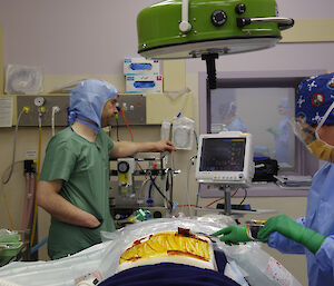 Members of the lay surgical team in surgical gowns in the theatre practising procedures