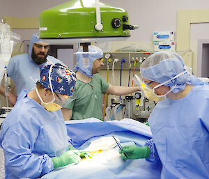 Members of the lay surgical team in surgical gowns in the theatre practising procedures