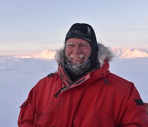 Expeditioner standing in foreground smiling with glacier in the background