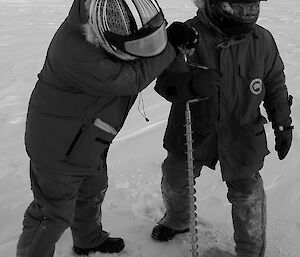 Two expeditioners manually drilling a hole into the sea ice