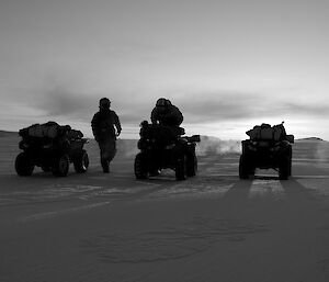 Four quad bikes and two expeditioners on sea ice.