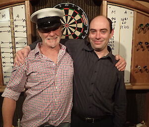Two expeditioners pose in front of dart board