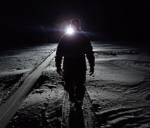 Expeditioner silhouetted by headlights