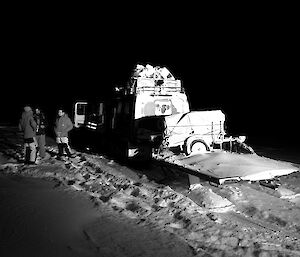 Expeditioners standing beside vehicles in the convoy illuminated by headlights