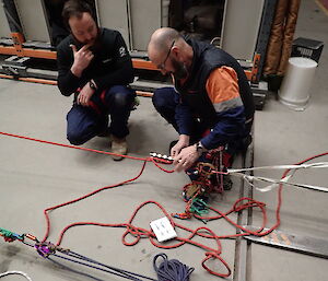 two expeditioners leaning beside a rescue rope working through a roping arrangement during technical training