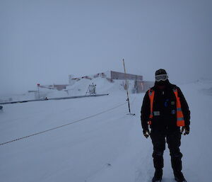 Expeditioner standing right of foreground.. workshop in background with overcast conditions