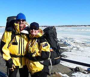 Two expeditioners with survival back packs facing camera with snow landscape in background