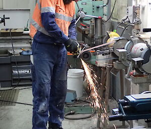 Expeditioner working with a linisher (mechanised grinder)