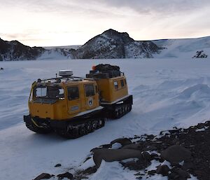 Yellow tracked vehicle in foreground. Plateau in background