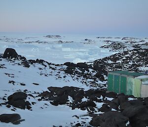 A field hut in foreground. Icebergs in background