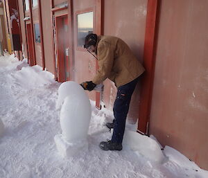 Expeditioner using a power tool to refine an ice sculpture