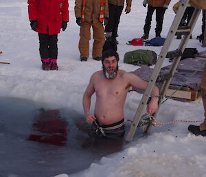 Expeditioner descends the ladder into the sea ice.