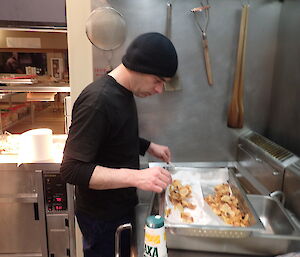 Expeditioner assisting in the kitchen at the deep fryer.