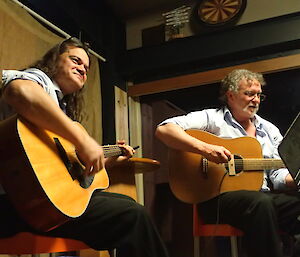 Two expeditioners playing guitar face the camera.