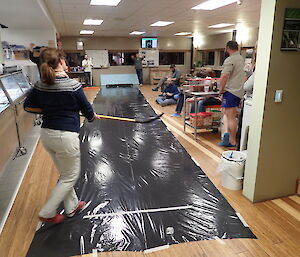 Expeditioner strikes a ice puck down a black plastic lane in the station ice hockey shootout