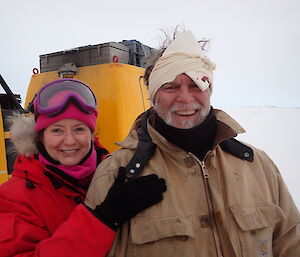 Two expeditioners, one with head bandaged facing the camera smiling.