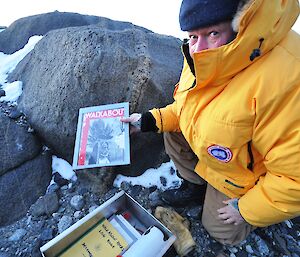 Expeditioner holding a copy of a dated magazine, one of several items of memorabilia stored at Walkabout Rocks
