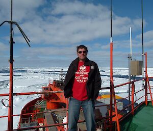 Expeditioner standing on the top deck of the Aurora Australis icebreaker with sea ice in background