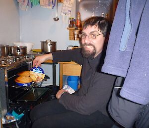 Expeditioner kneeling next to an oven with a Fray Bentos at the ready