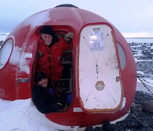 Two expeditioners facing out of a field hut