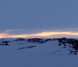 Sunlight filtering through an overcast horizon with icebergs silhouetted