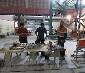 Three expeditioners standing behind a trestle table self serving food