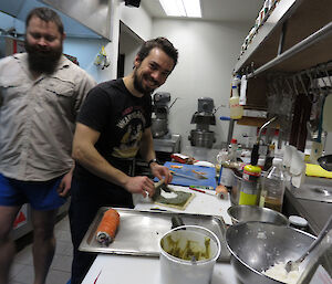 Two expeditioners facing camera working in kitchen