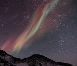 Red and green aurora suspended over the hills behind Platcha hut