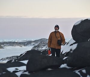 Expeditioner walking around rocky outcrops covered in snow