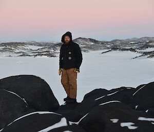 Expeditioner standing on top of rocky outcrop facing camera