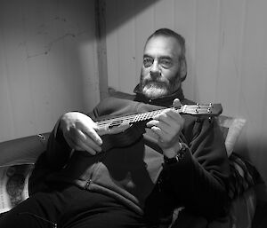 Expeditioner reclining on a bunk bed playing a ukelele