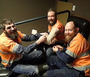 three expeditioners, one with a bandaged arm smiling at camera