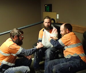 Three expeditioners facing camera two smiling one with a bandaged arm frowning