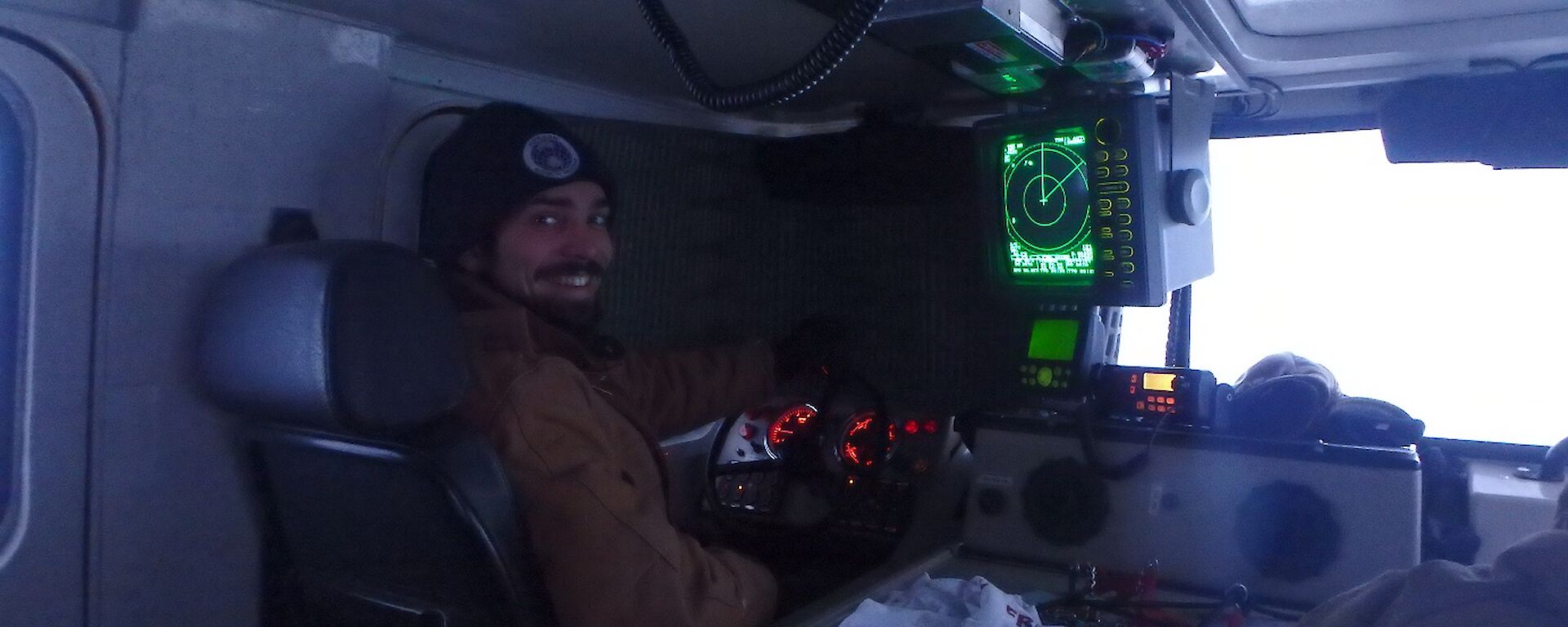 Expeditioner in driver seat of Hägglunds with windows blacked out driving by radar, facing camera