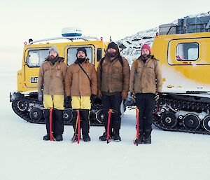 Four expeditioners standing rigid to attention in front of a yellow tracked vehicle