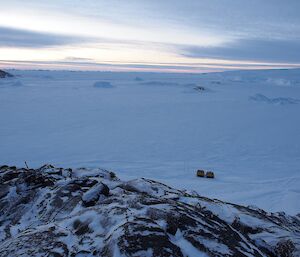 Rock terrain looking down at Hagg vehicle situated on the sea ice below