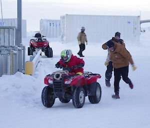 Expeditioner riding a quad having been pushed by two other expeditioners with others spectating