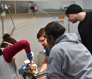 Expeditioners gathered around a dentist’s chair observing a procedure with a mannequin