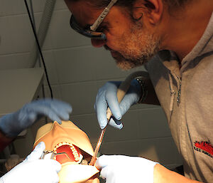 Expeditioner seated beside a mannequin demonstrating dental procedures