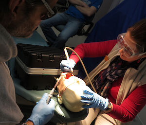 Expeditioner leaning over a mannequin demonstrating dental procedures